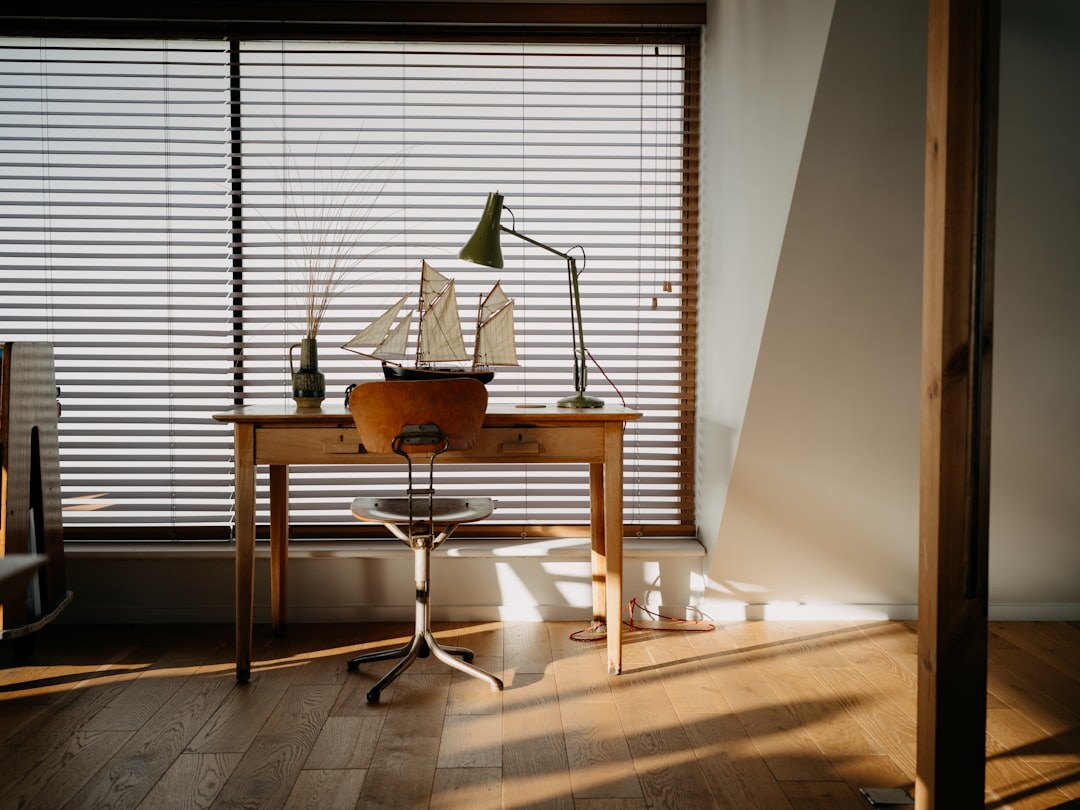 Camera and notebook on a wooden desk by a window